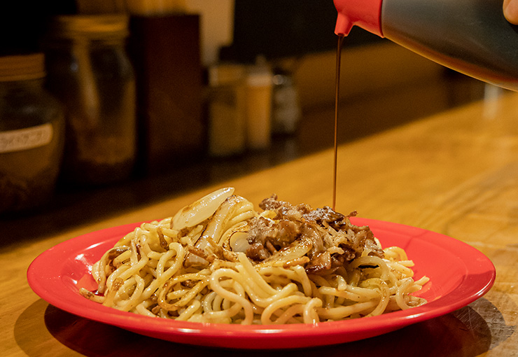 焼きそばにソースをかけている画像